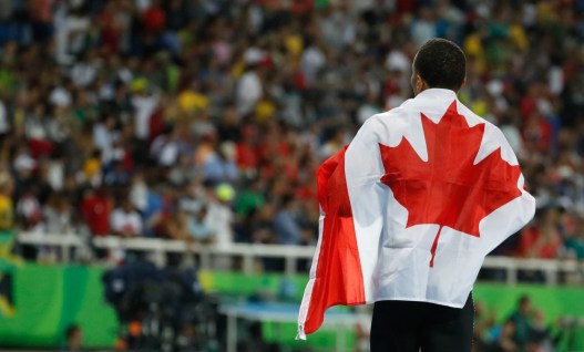 Canada's Andre De Grasse celebrates with his nation's flag after earning a silver medal in the men's 200m final in Rio on August 18, 2016. (photo/ Mark Blinch)