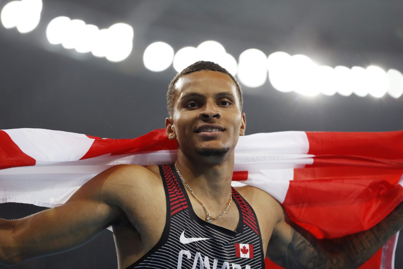 Canada's Andre De Grasse celebrates with his nation's flag after earning a silver medal in the men's 200m final in Rio on August 18, 2016. (photo/ Stephen Hosier)