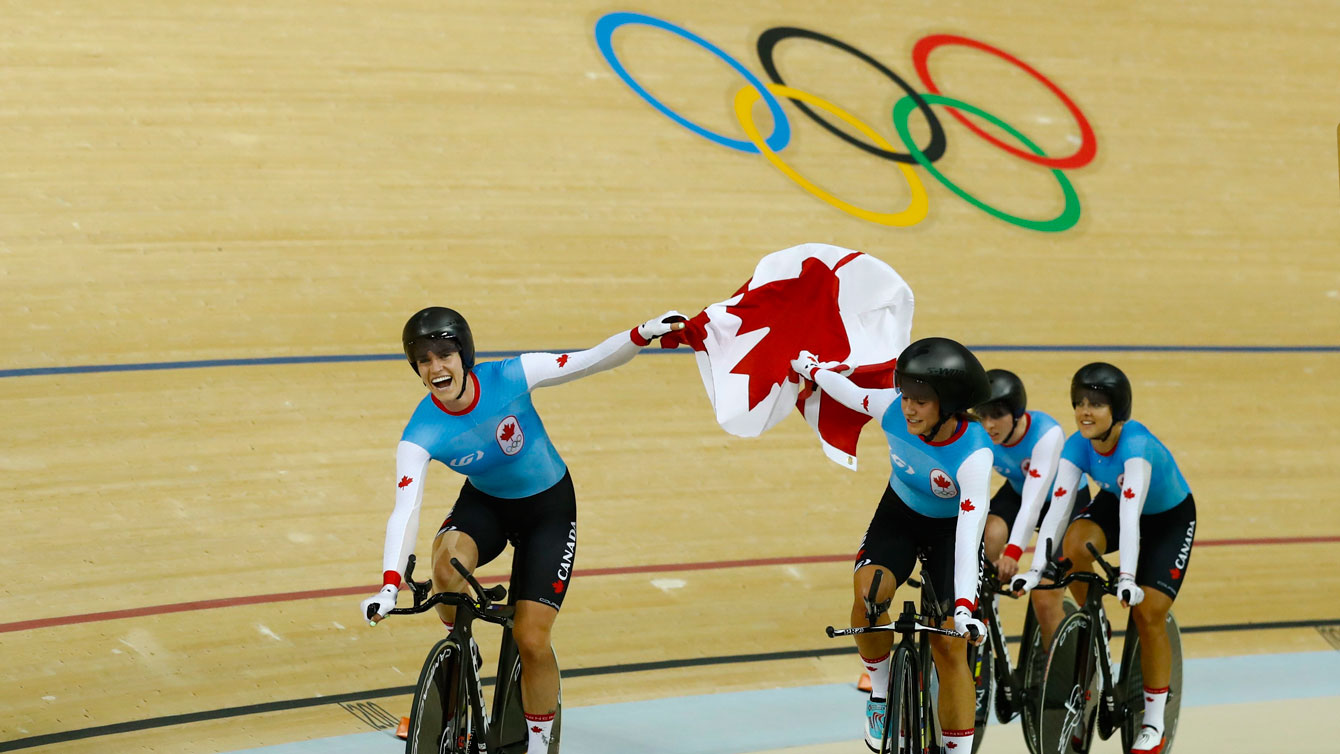 Canada's team pursuit riders lift the flag following their Olympic bronze medal win over New Zealand in Rio de Janeiro on August 13, 2016. 