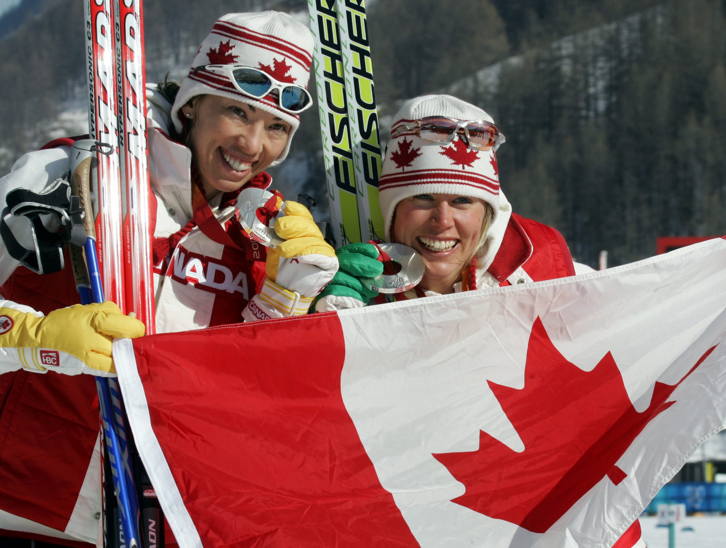 Beckie Scott, left, and Sara Renner pose with the Canadian flag as they display their silver medals 
