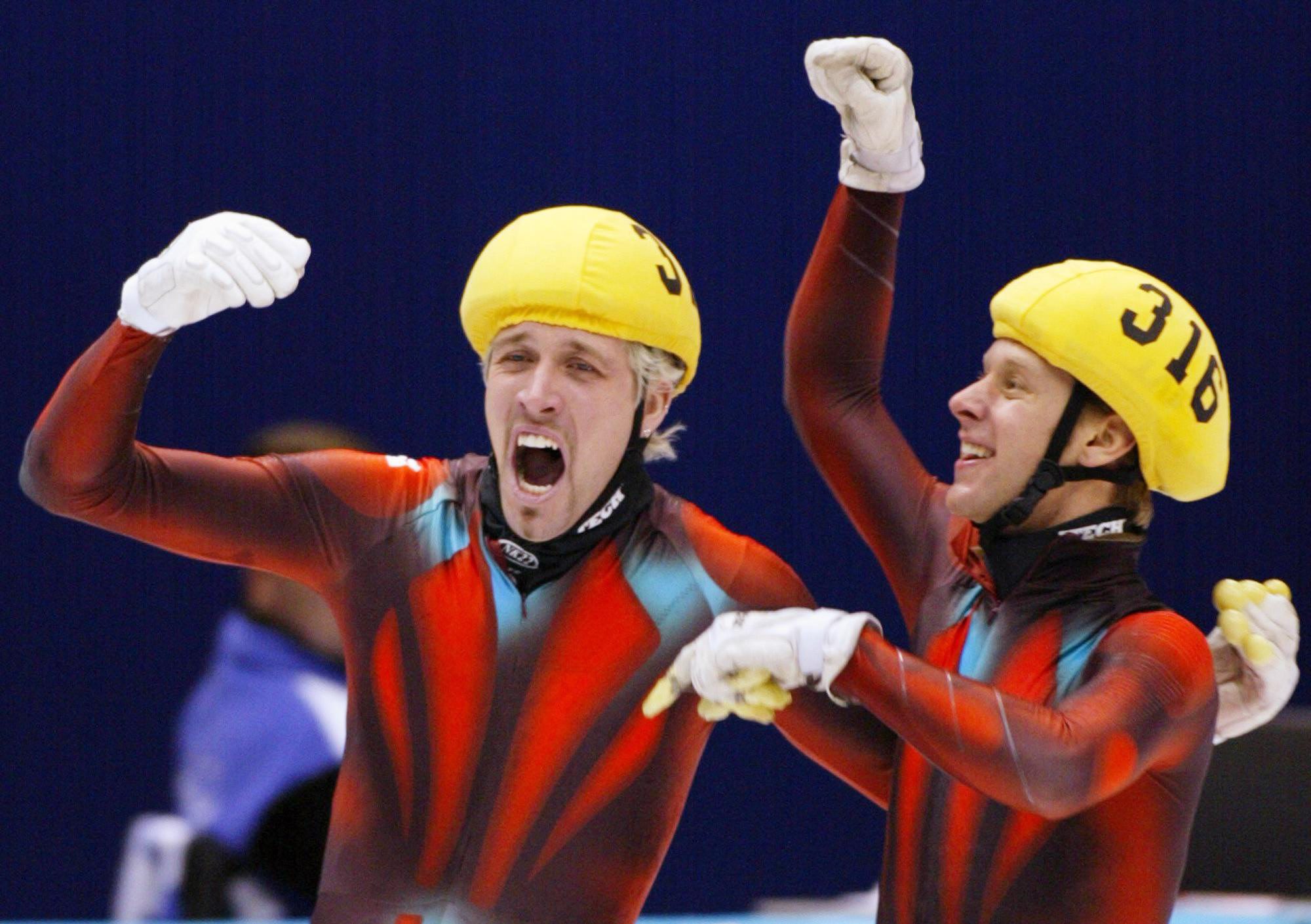 Two speed skaters celebrate with arms up