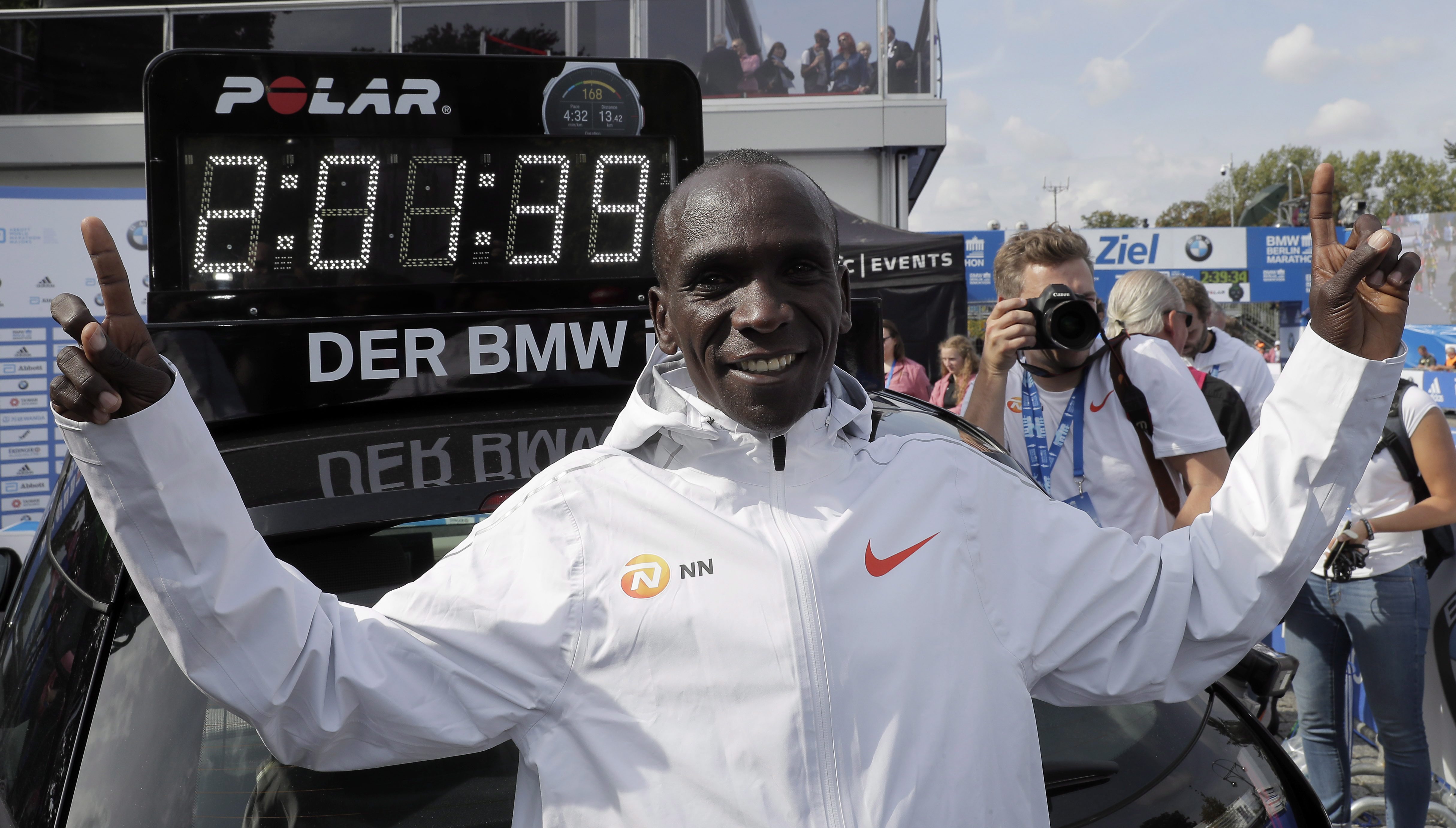 Eliud Kipchoge in front of the clock showing his world record time 