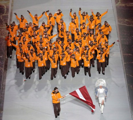 Sandis Ozolins of Latvia holds his national flag and enters the arena with teammates during the opening ceremony of the 2014 Olympic Winter Games in Sochi, Russia, Friday, Feb. 7, 2014. (AP Photo/Charlie Riedel)