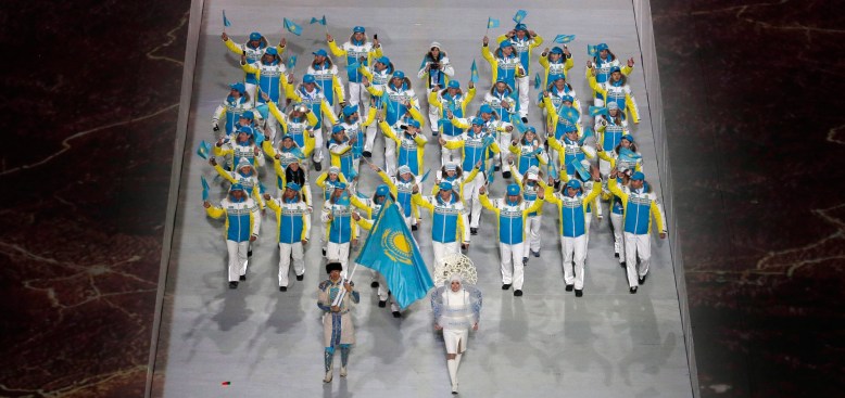 Yerdos Akhmadiyev of Kazakhstan holds the national flag and enters the arena with his teammates during the opening ceremony of the 2014 Olympic Winter Games in Sochi, Russia, Friday, Feb. 7, 2014. (AP Photo/Charlie Riedel)