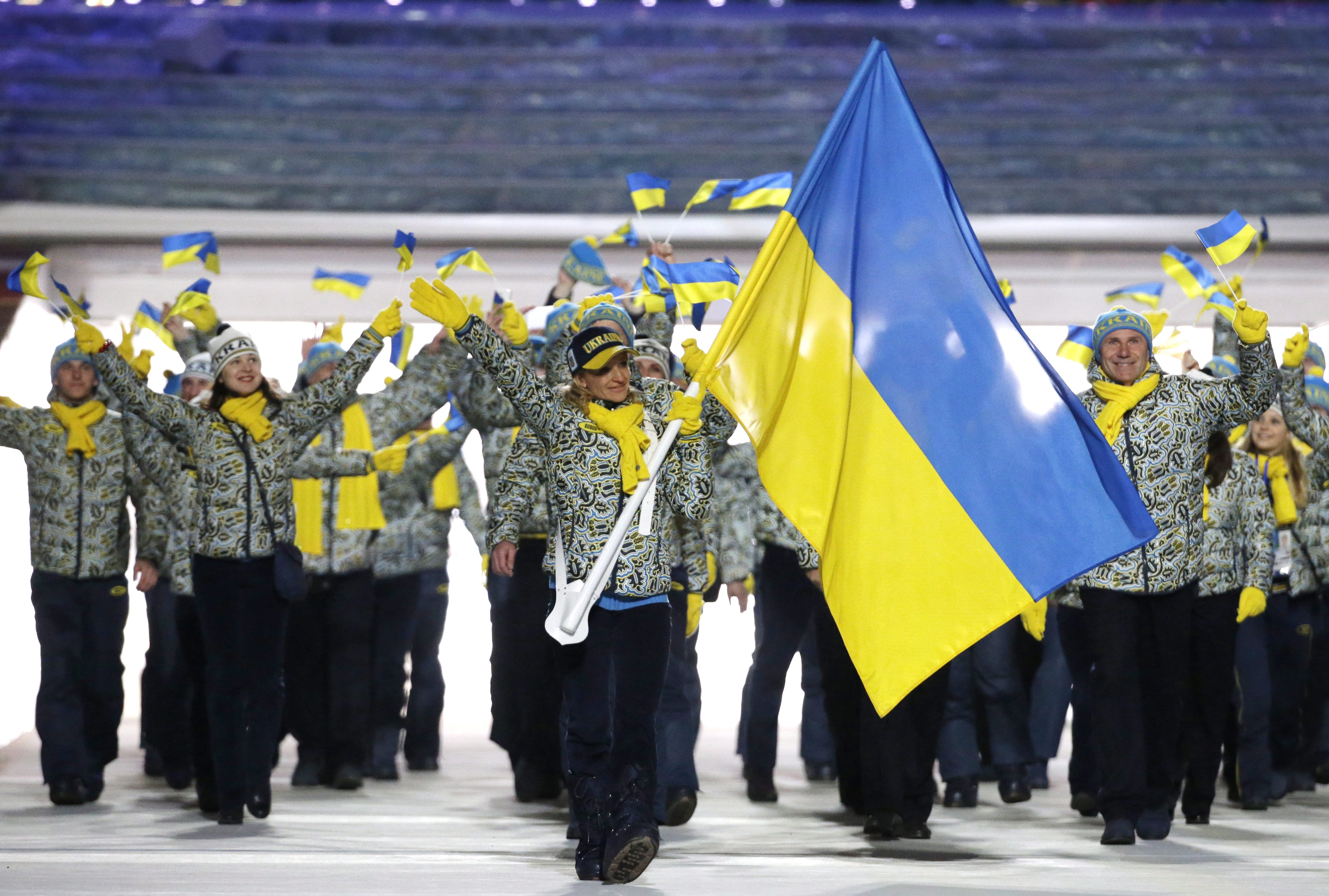 Valentina Shevchenko of Ukraine carries the national flag as she leads the team during the opening ceremony of the 2014 Olympic Winter Games in Sochi, Russia, Friday, Feb. 7, 2014. (AP Photo/Mark Humphrey)
