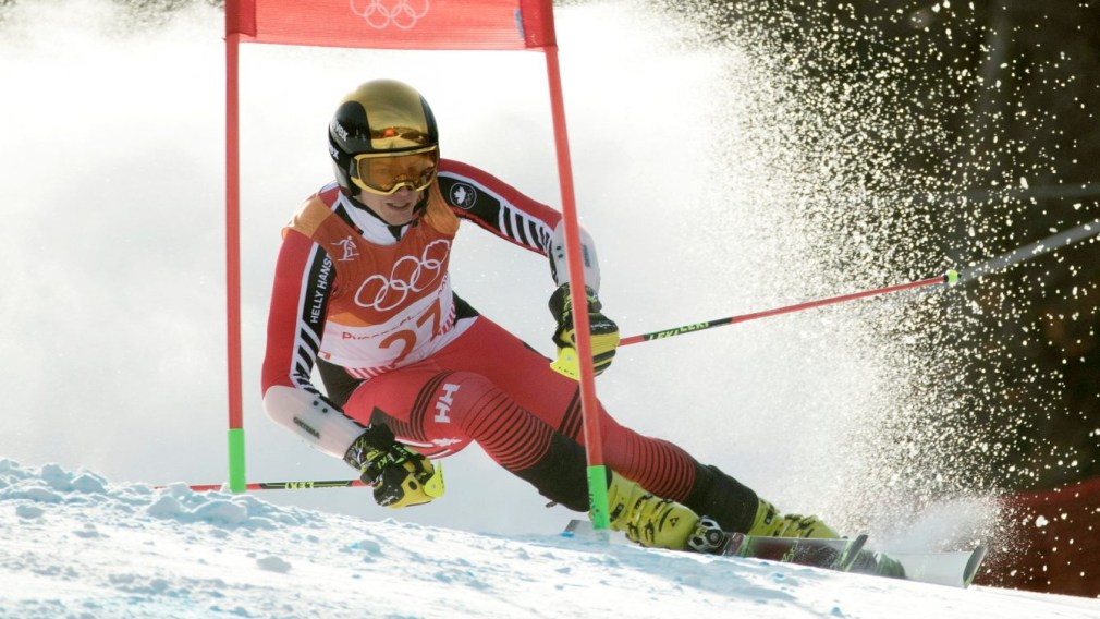 Erik Read mid-competition in the giant slalom at PyeongChang 2018. He is wearing a red, orange and white suit, and a chrome yellow helmet with matching goggles.