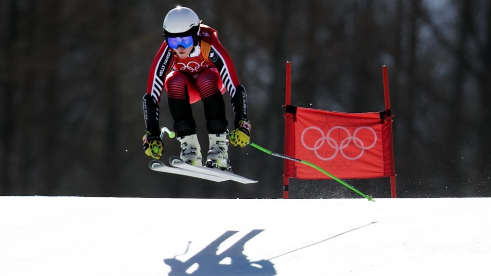 Alpine skier and her shadow going over a jump