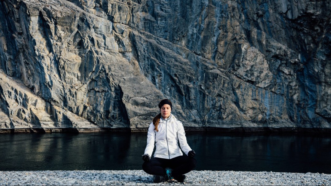 Steph Labbe meditates by a lake and mountains