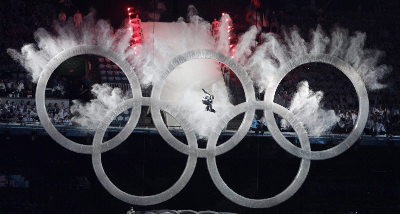 A snowboarder sailing through the Olympic rings during the Opening Ceremonies of Vancouver 2010