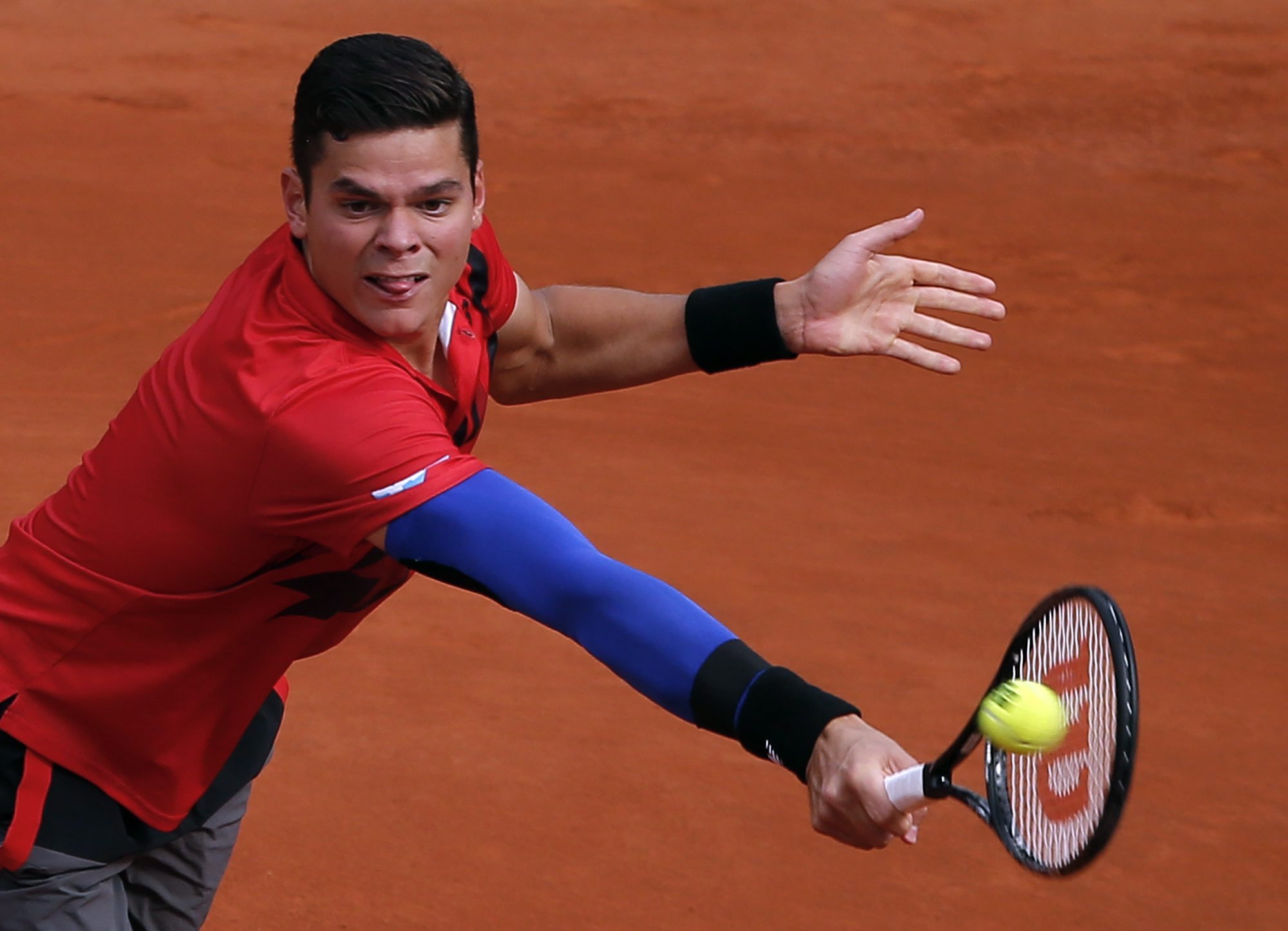 Milos Raonic backhands the ball