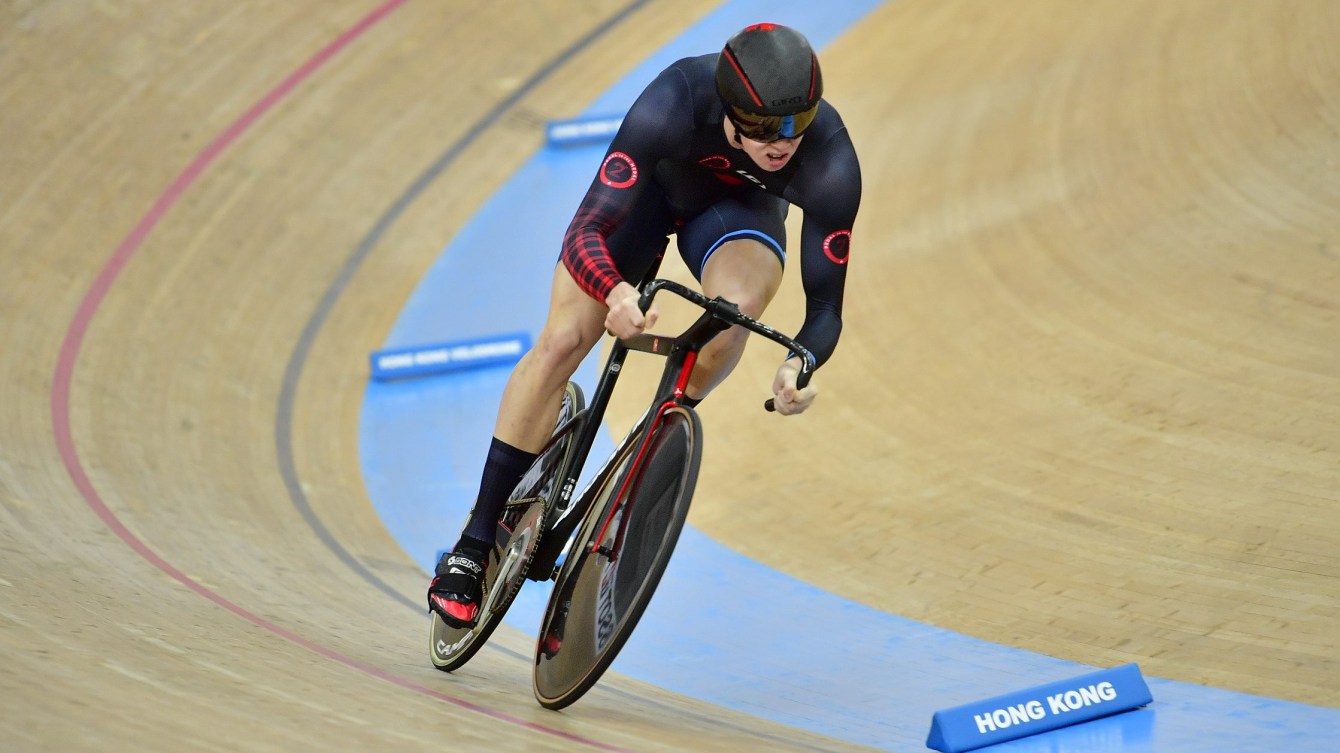 Nick Wammes making a turn on the track. He is in a black and red cycling suit. 