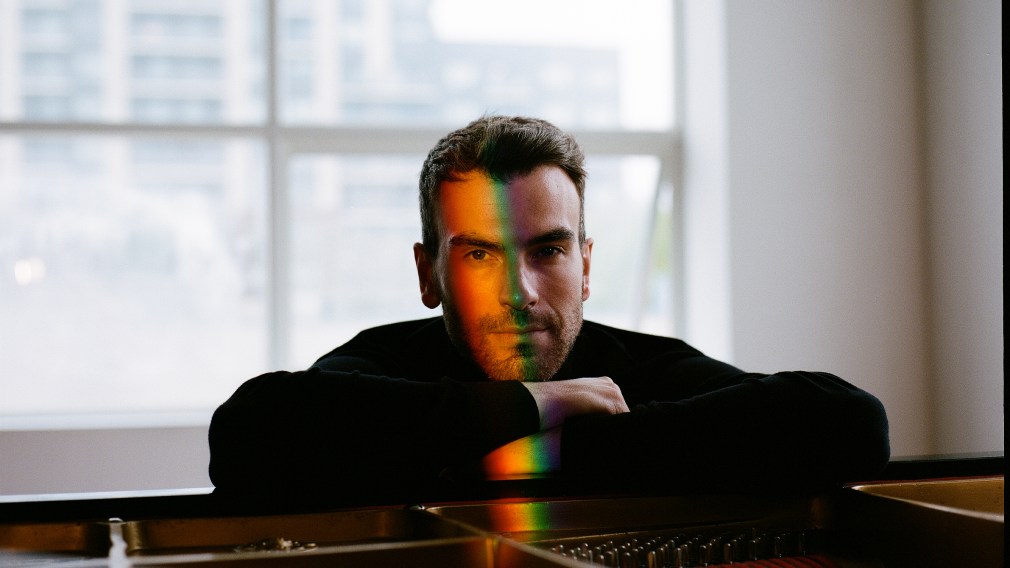 Man sitting at piano with rainbow light on face