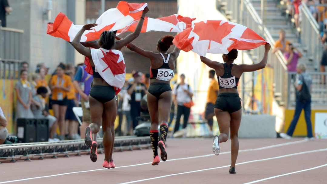 Three Canadian athletes running with flag