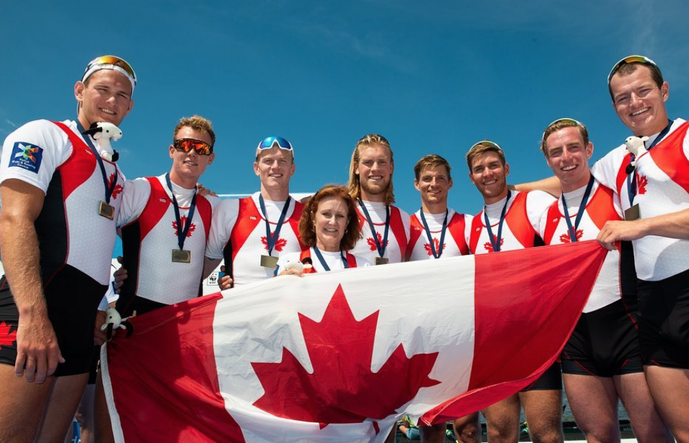 Team Canada standing in front of flag with bronze medals.