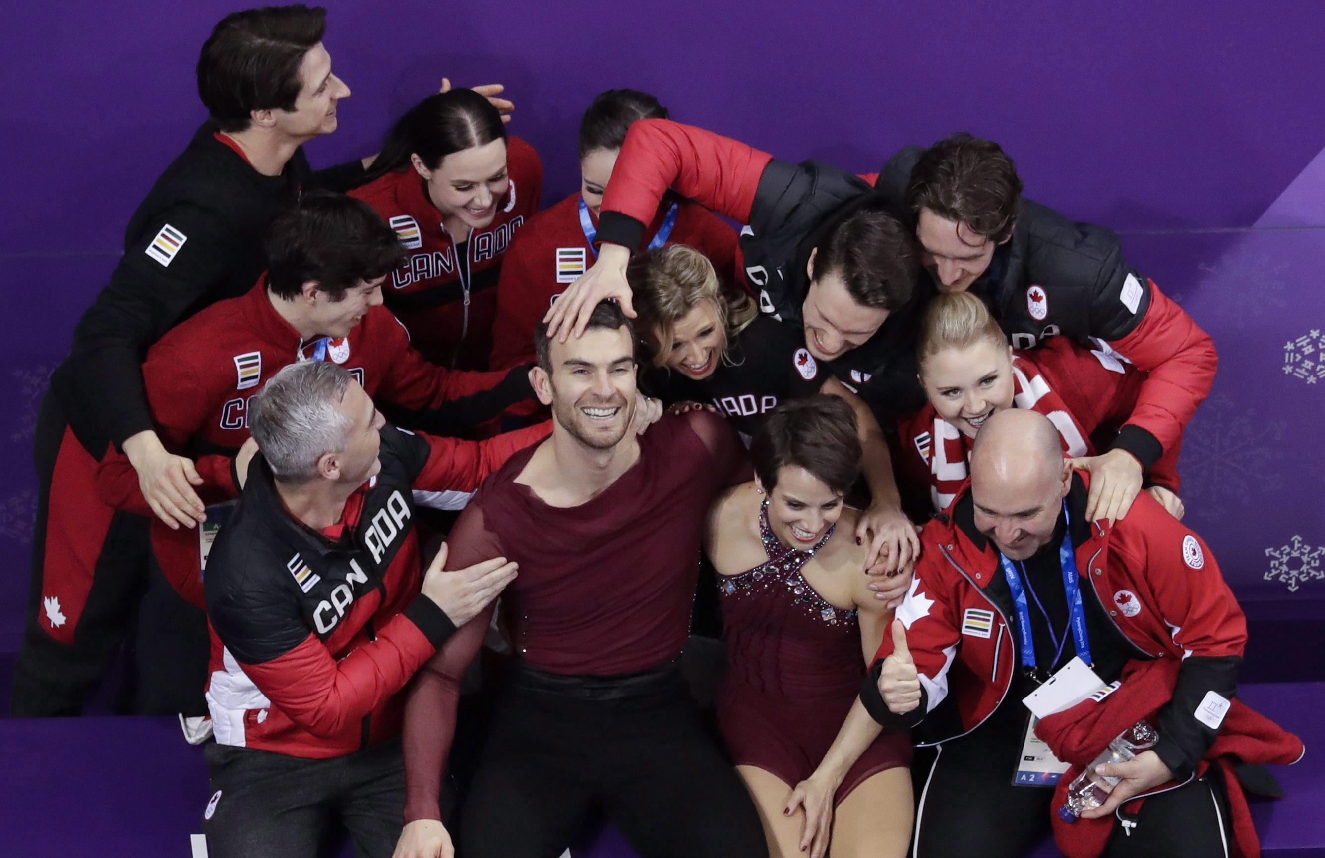 Meagan Duhamel and Eric Radford and Team Canada athletes celebrating after performance.