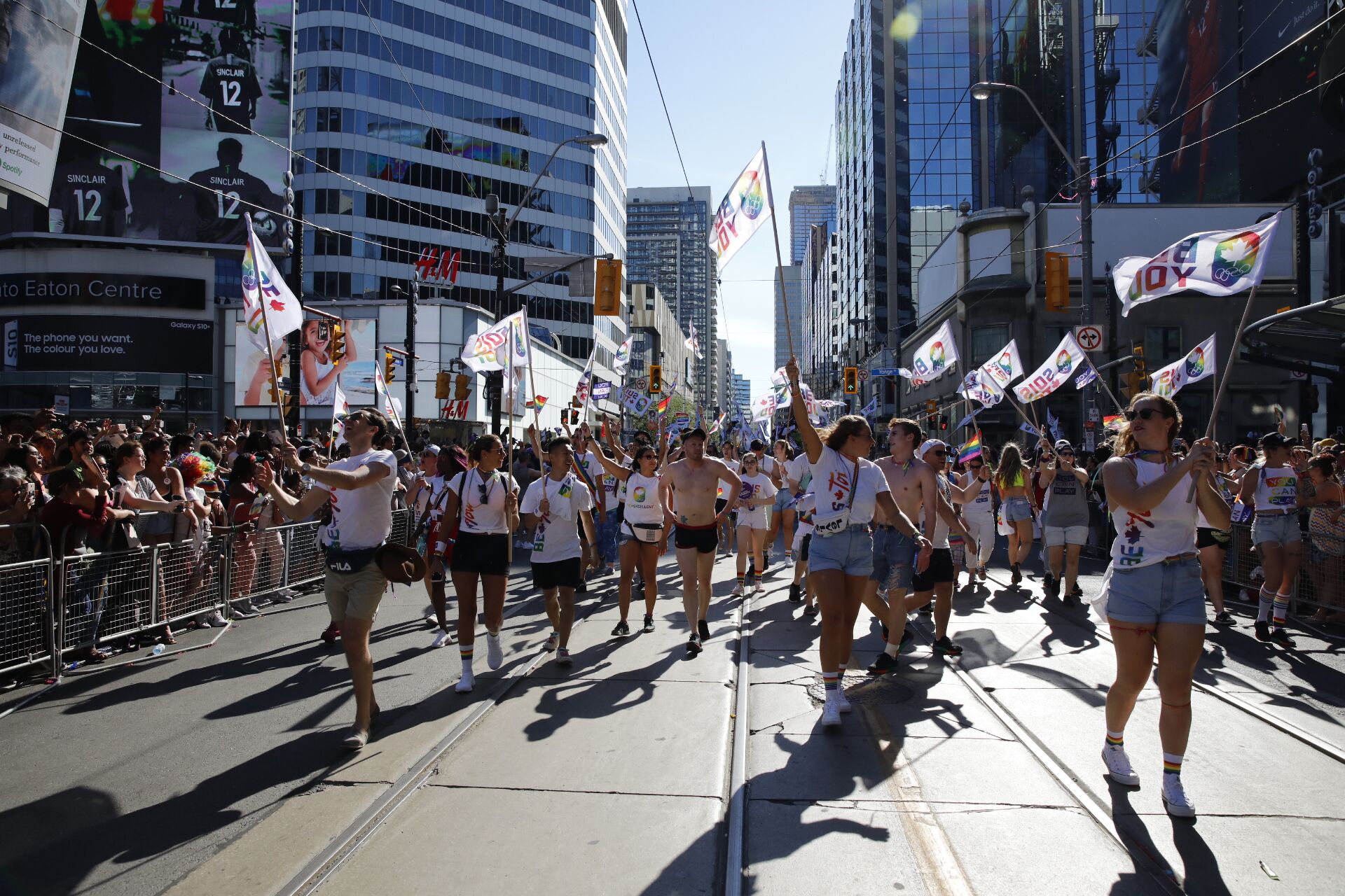 The Team Canada squad march in the Pride Parade holding flags.