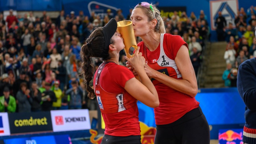 Volleyball players kiss their trophy after the big win