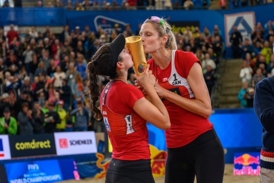 Volleyball players kiss their trophy after the big win