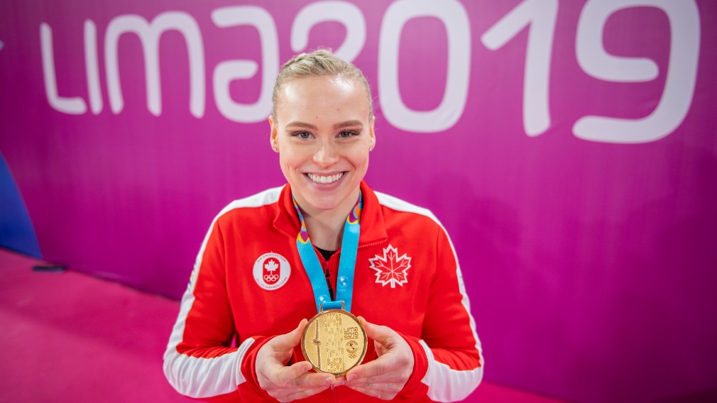 Athlete poses with her gold medal in front of Lima 2019 sign