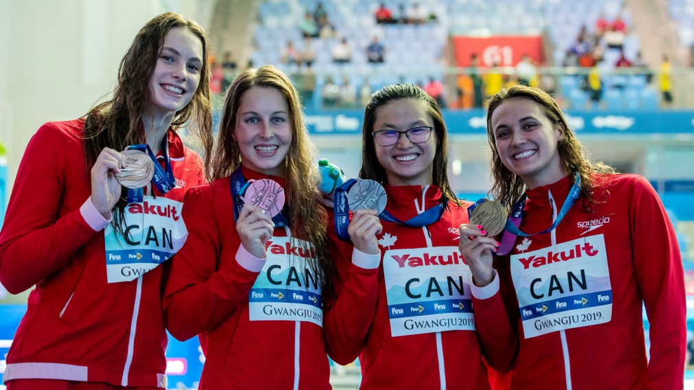 Four swimmers pose with medals