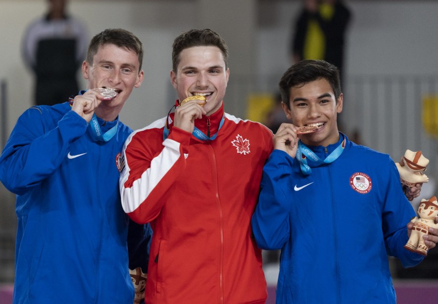 three athletes on the podium bite their medals