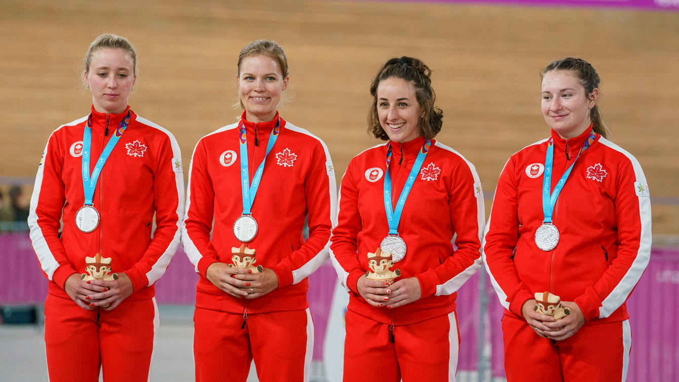 women's team stand on the podium wearing gold medals