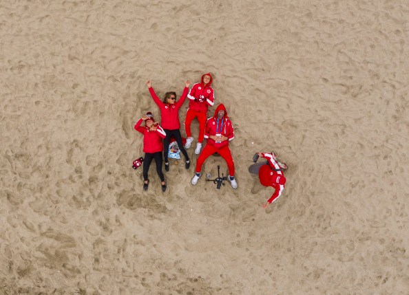 Surfers in their Team Canada Kits lay on the sand