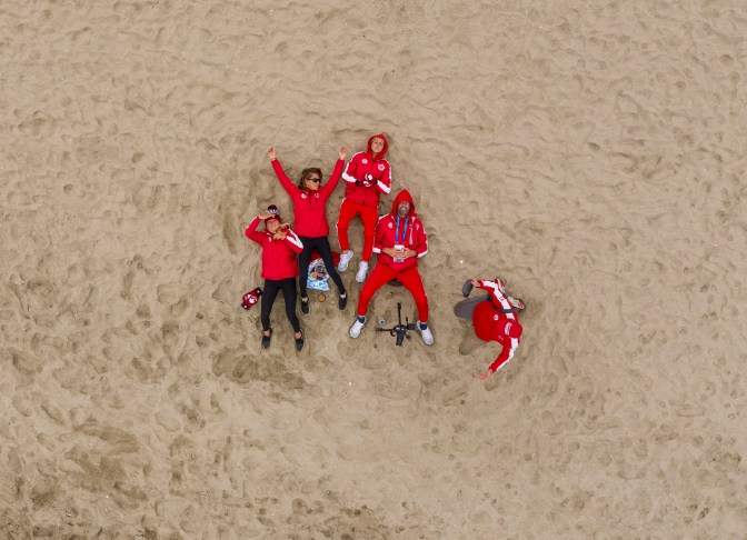 Surfers in their Team Canada Kits lay on the sand