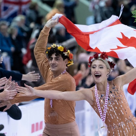 Piper Gilles and Paul Poirier reach out to the crowd during victory ceremonies at Skate Canada