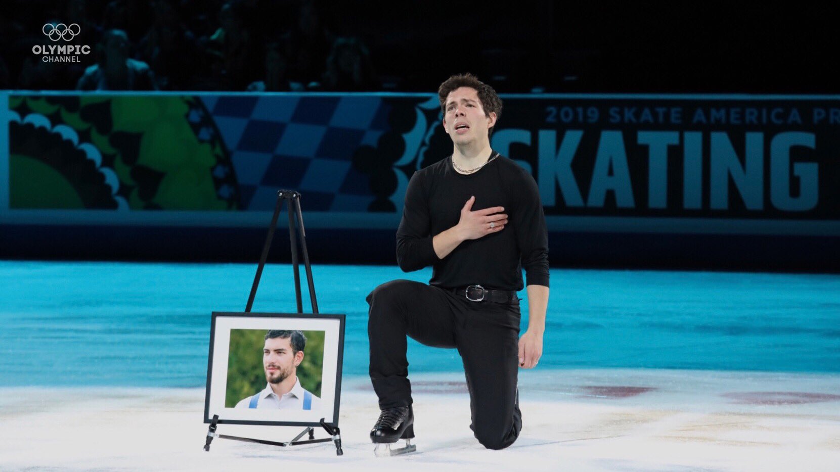 Keegan Messing kneels beside a picture of his late brother