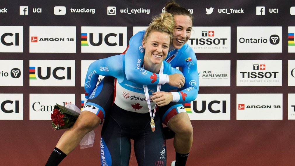 Lauriane Genest gets a piggyback ride from Kelsey Mitchell after receiving their gold medals on the podium.