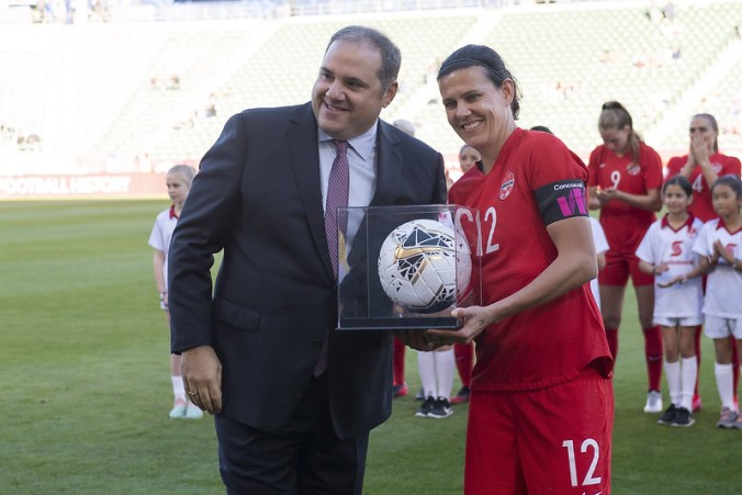 Christine Sinclair is given her record-breaking game ball by Victor Montagliani