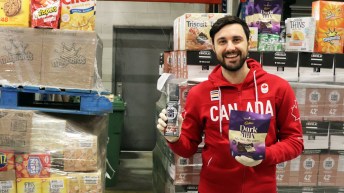 Joseph Polossifakis holds onto a back of Cadbury Dark Milk mini bars in his left hand and a Core Power Elite Drink in the other.