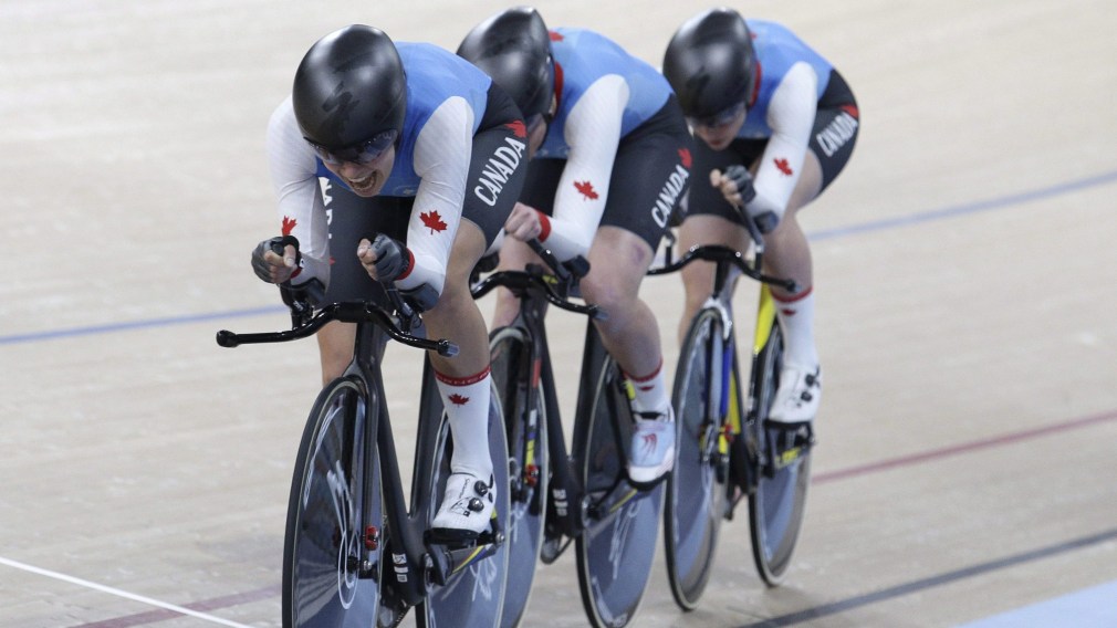 Three cyclists race team pursuit in a velodrome