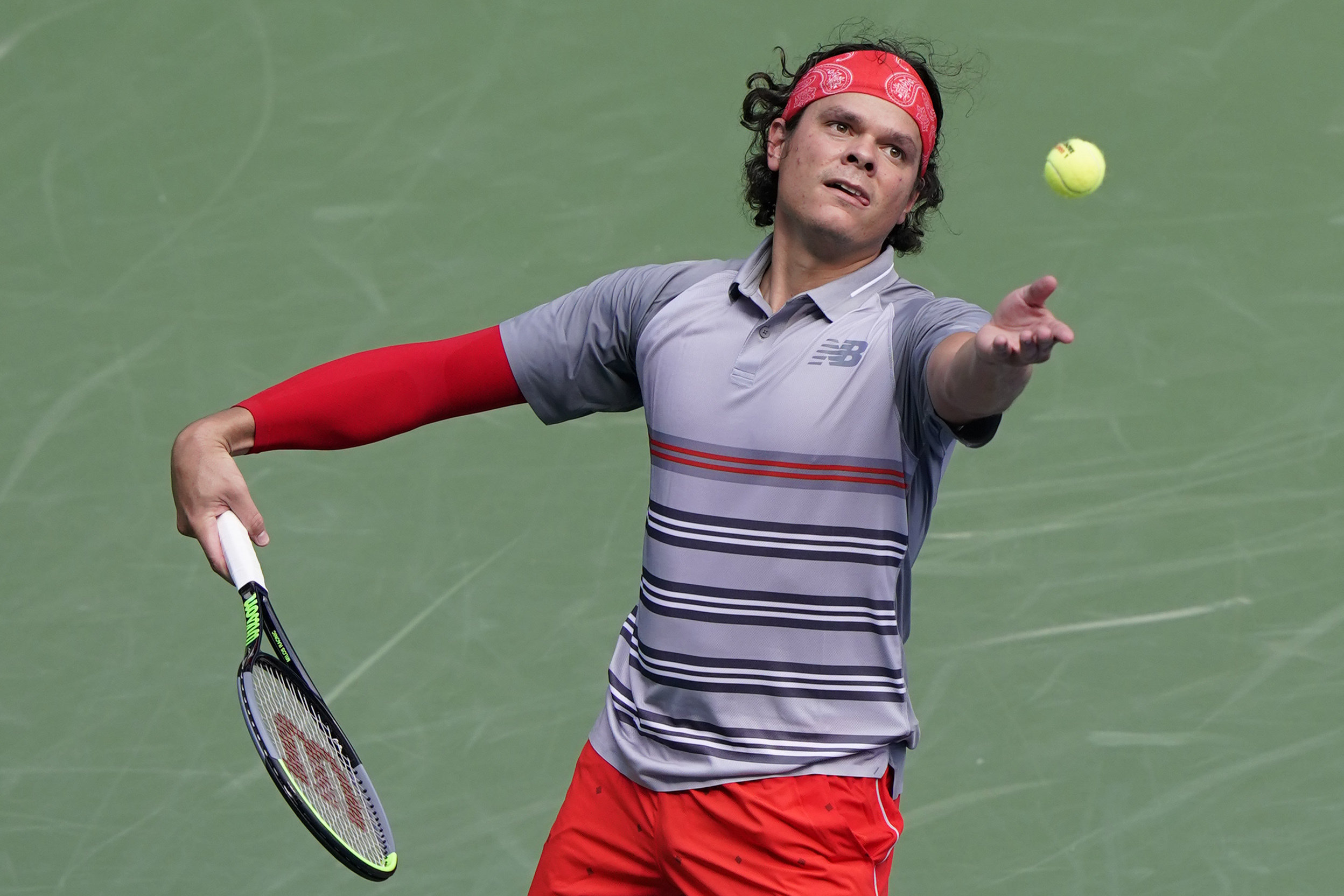 Milos throws the ball in the air to serve it.