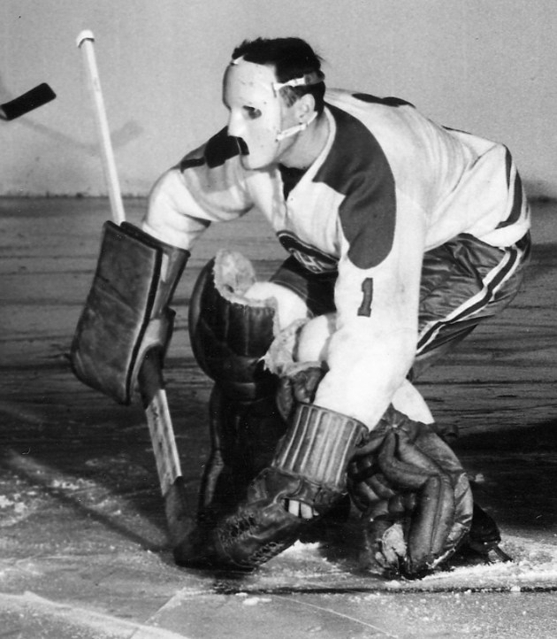 Jacques Plante squatting down in front of the goalie net in 1959 wearing his mask during a game against the Toronto Maple Leafs at Madison Square Garden.