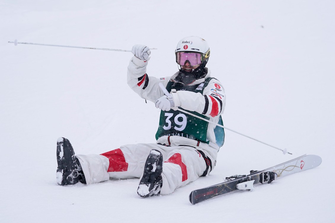 Mikaël Kingsbury sits on the ground after winning gold.