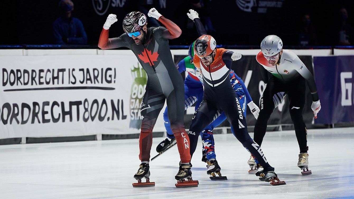 Charles Hamelin raises arms in celebration as he beats his competitors to the finish line