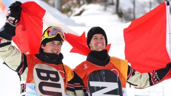 Mark McMorris (left) holds up the Canadian flag behind him with Max Parrot.