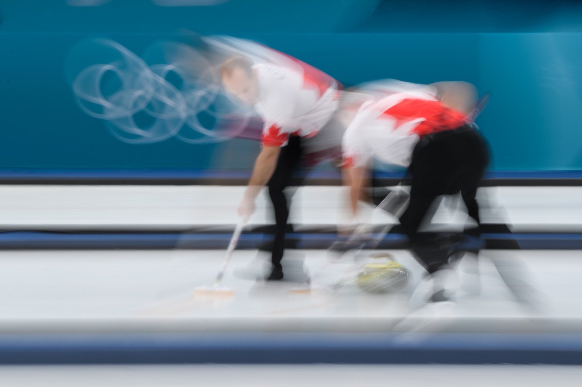 Blurry photo of two curlers sweeping