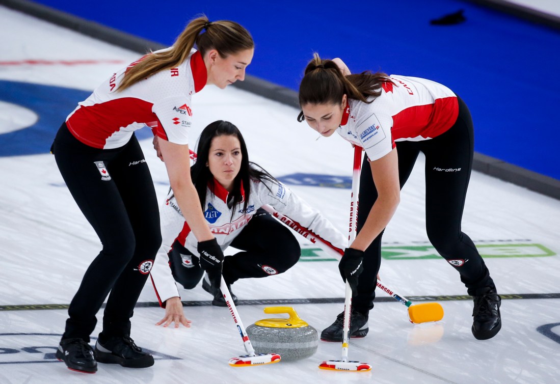 Kerri Einarson makes a shot as lead Briane Meilleur, left, and second Shannon Birchard sweep