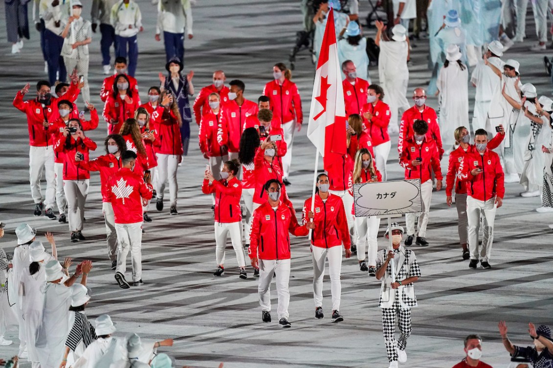 Team Canada walks into the Tokyo 2020 opening ceremony wearing red jackets and white pants 