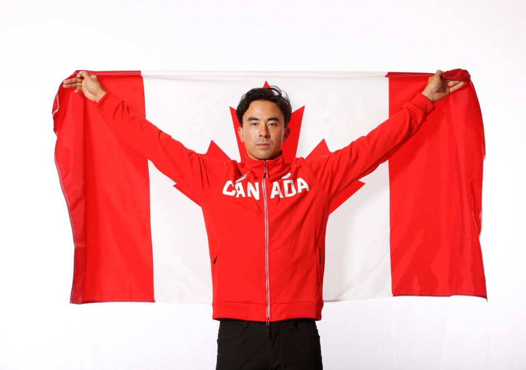 Nathan Hirayama holds Canadian flag over shoulders