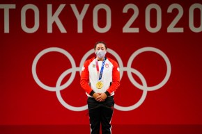 Weightlifter Maude Charron stands with her eyes closed, gold medal around her neck, in front of a wall reading Tokyo 2020.