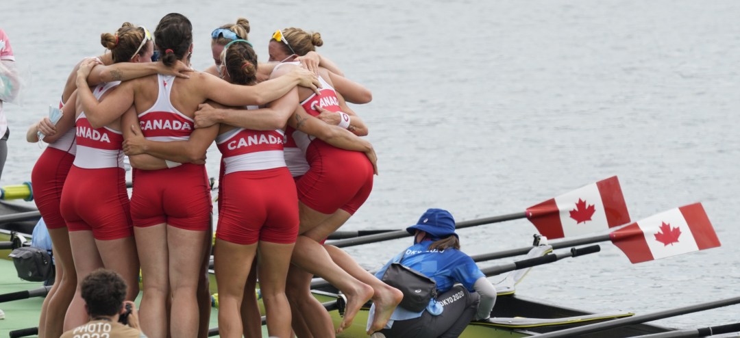 Rowing team hugs in a huddle on the dock