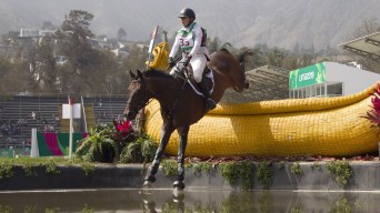 Equestrian rider and horse jumping over water obstacle
