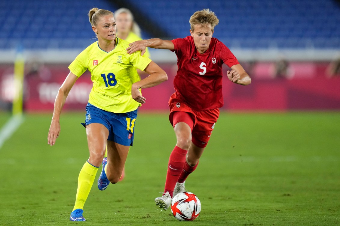 Quinn battles for the ball with a Swedish opponent