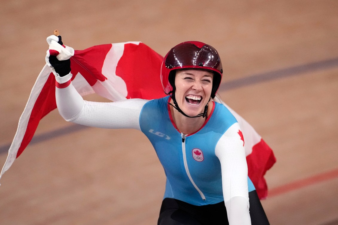 Kelsey Mitchell waves the Canadian flag while doing a victory lap at the velodrome