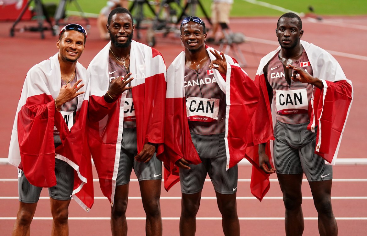Canada's men's 4x100m relay team poses with the Canadian flag