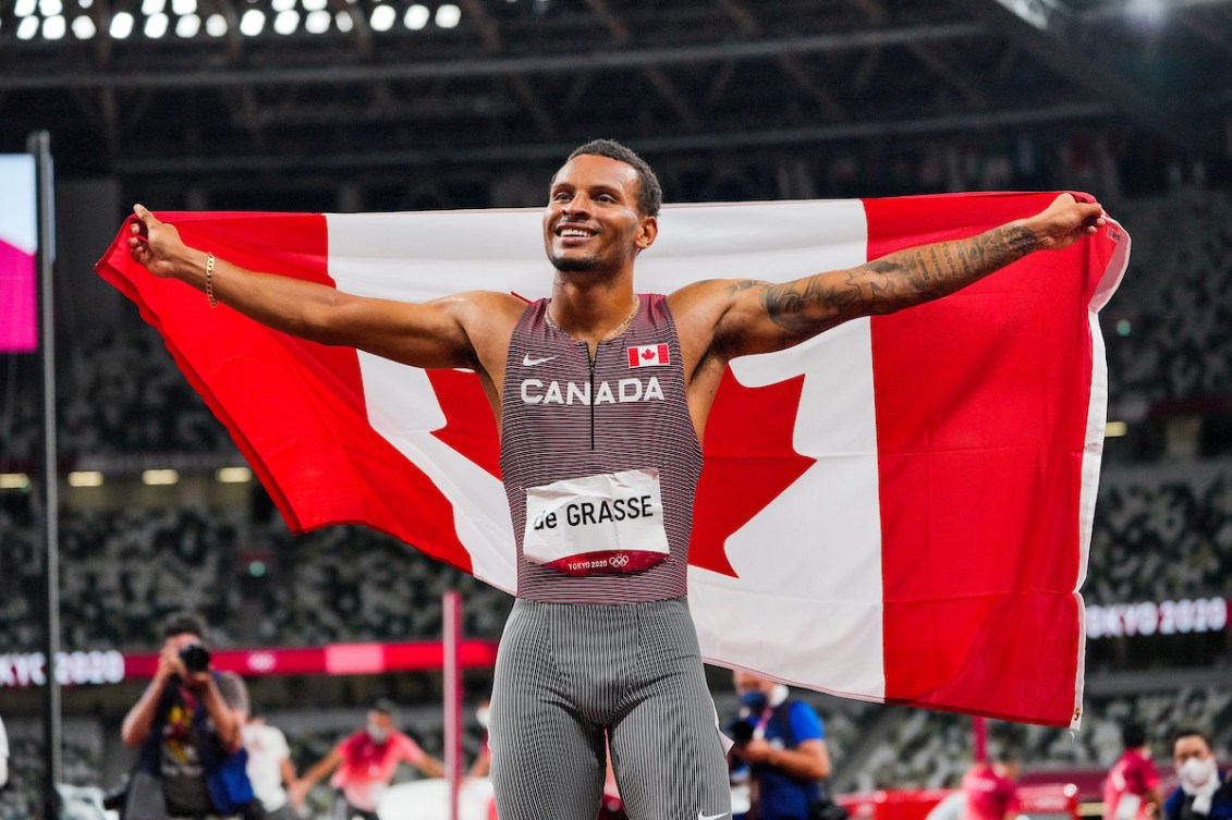 Andre De Grasse raises the Canadian flag after winning the 200-metre final 